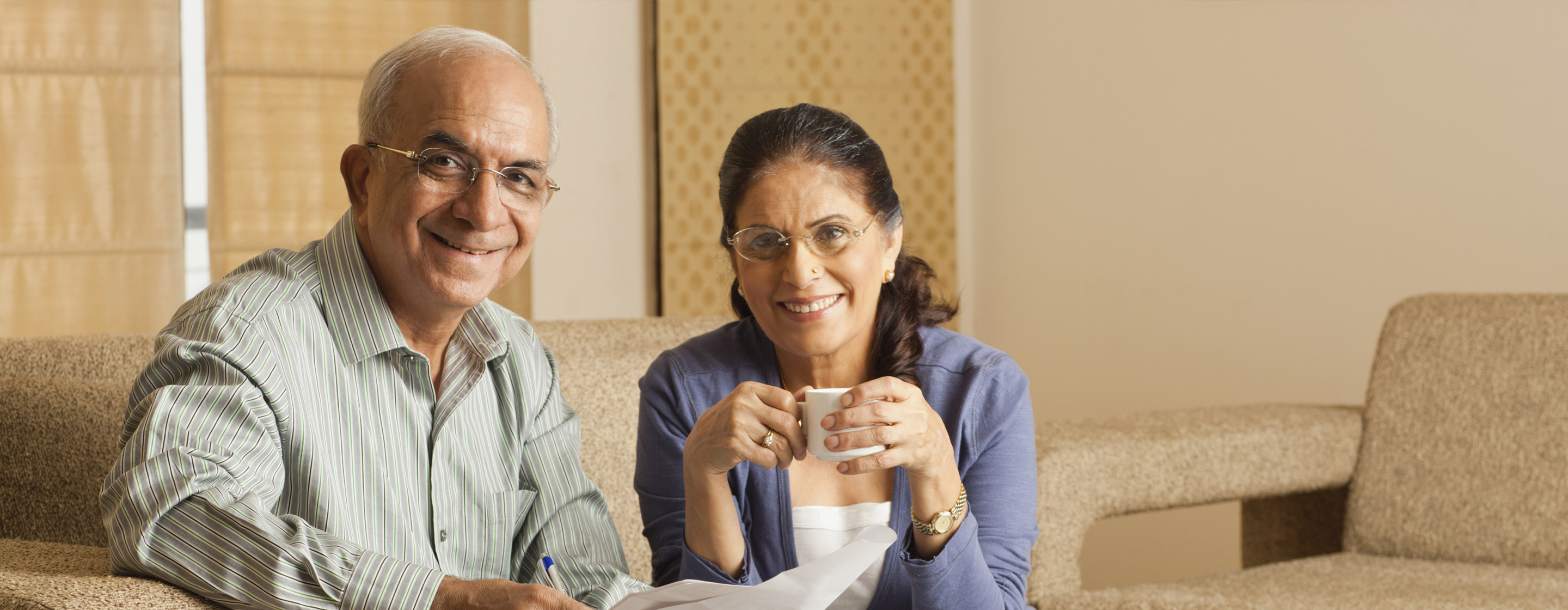 Portrait of senior couple working in living room, with laptop on coffee table