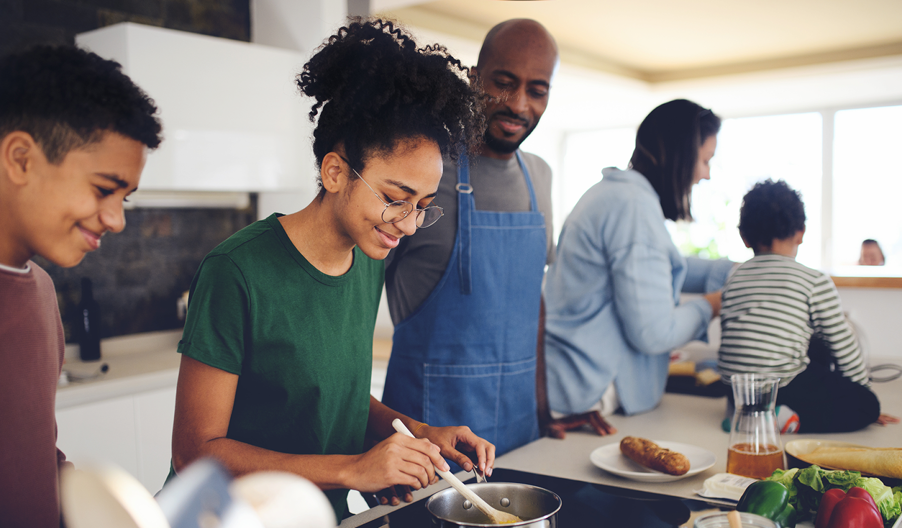 Smiling family in a kitchen cooking together, with a mother and son preparing food at the counter