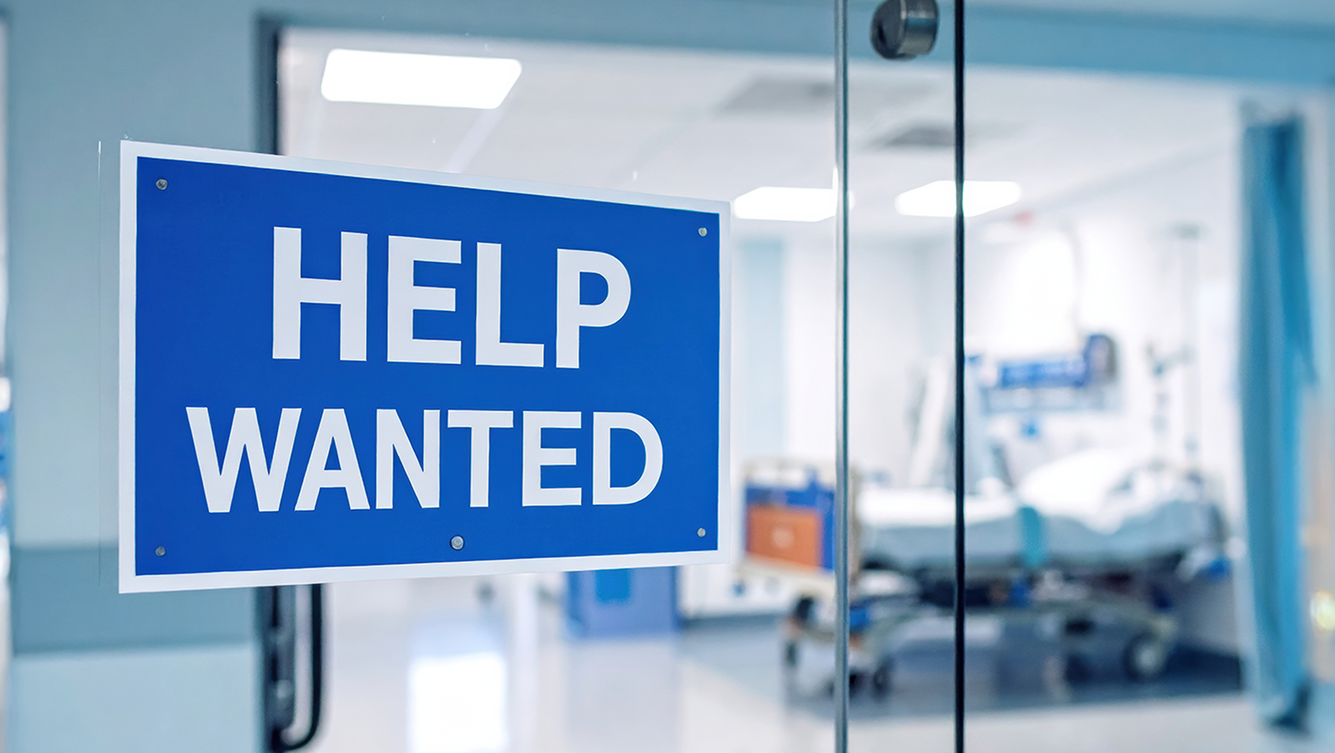 A help wanted sign is posted on the doors to an emergency room.