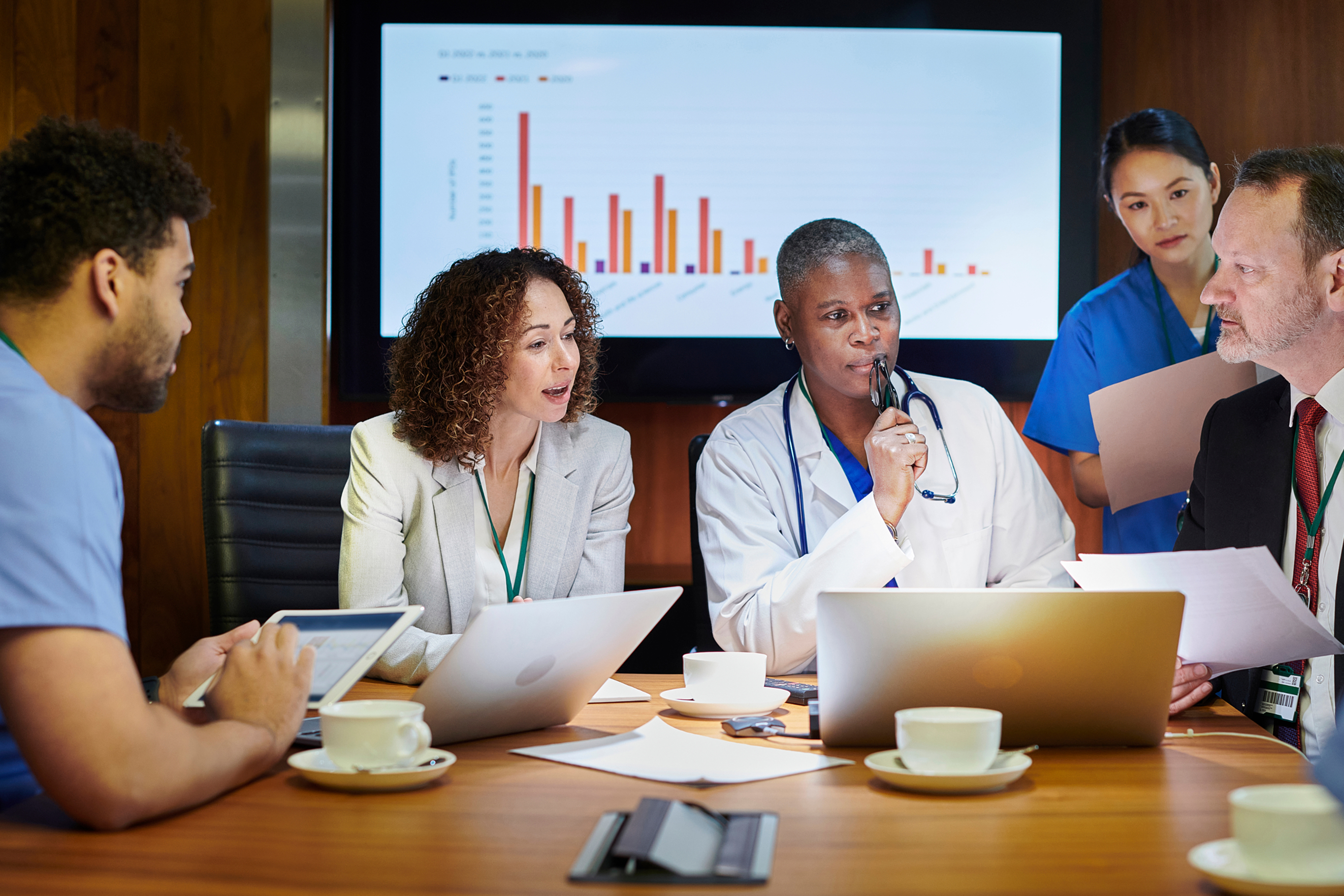 Male consultant meets with male and female medical professionals in a conference room to discuss benefits plans.