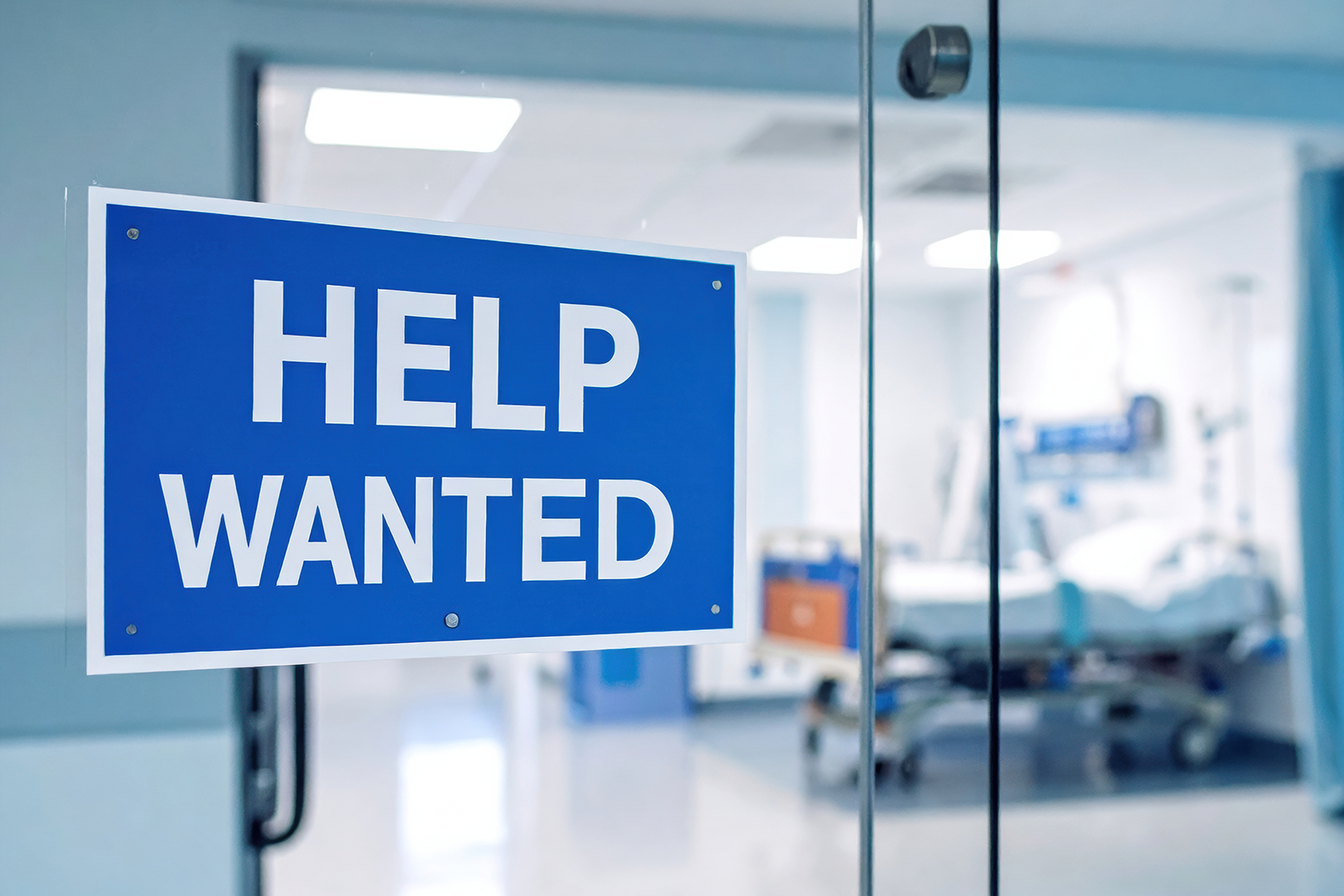 A help wanted sign is posted on the doors to an emergency room.