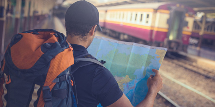 Young man reviews a map near train station while on vacation