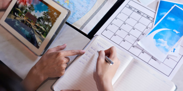 Person writing out a travel budget in a notebook